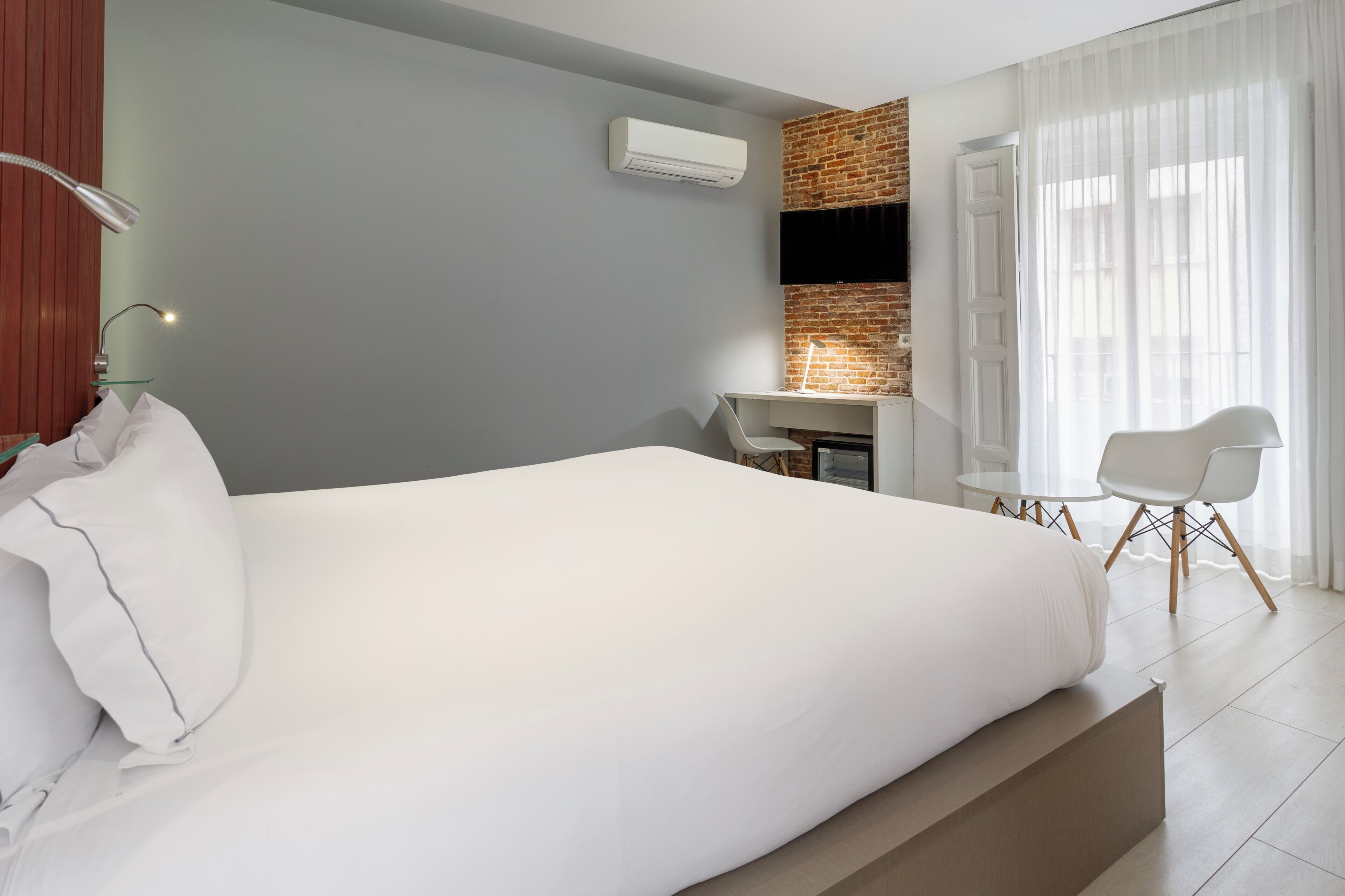 Una habitación de hotel moderna con una cama grande, un escritorio y una zona de estar.