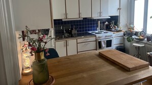 Une cuisine avec des armoires blanches, un dosseret de carreaux bleus, une cuisinière et un plan de travail en bois.