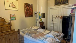 Une chambre à coucher avec un lit en bois, une commode, une plante en pot et un tableau accroché au mur.
