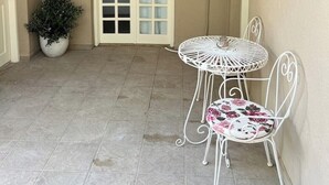 A covered patio with a white door, a potted plant, and a table with chairs. - Ruby Apartment (Αγιος Νικολαος)