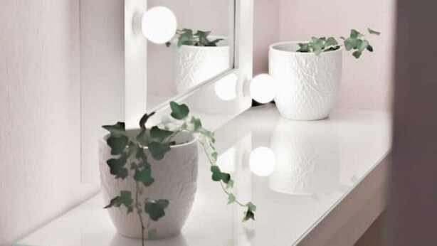 A bathroom vanity with a mirror, lights, and two potted plants. - Ruby Apartment (Αγιος Νικολαος)