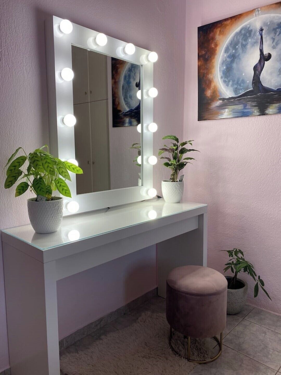 Un espacio de tocador con un espejo grande, iluminación y plantas en macetas.