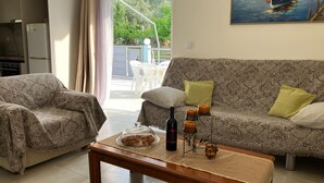 Una sala de estar con un sofá estampado, una mesa de centro de madera con adornos y un cuadro de barcos en la pared.