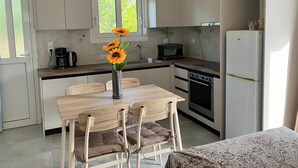 Una cocina moderna con una mesa de comedor, sillas, cafetera, estufa y refrigerador.