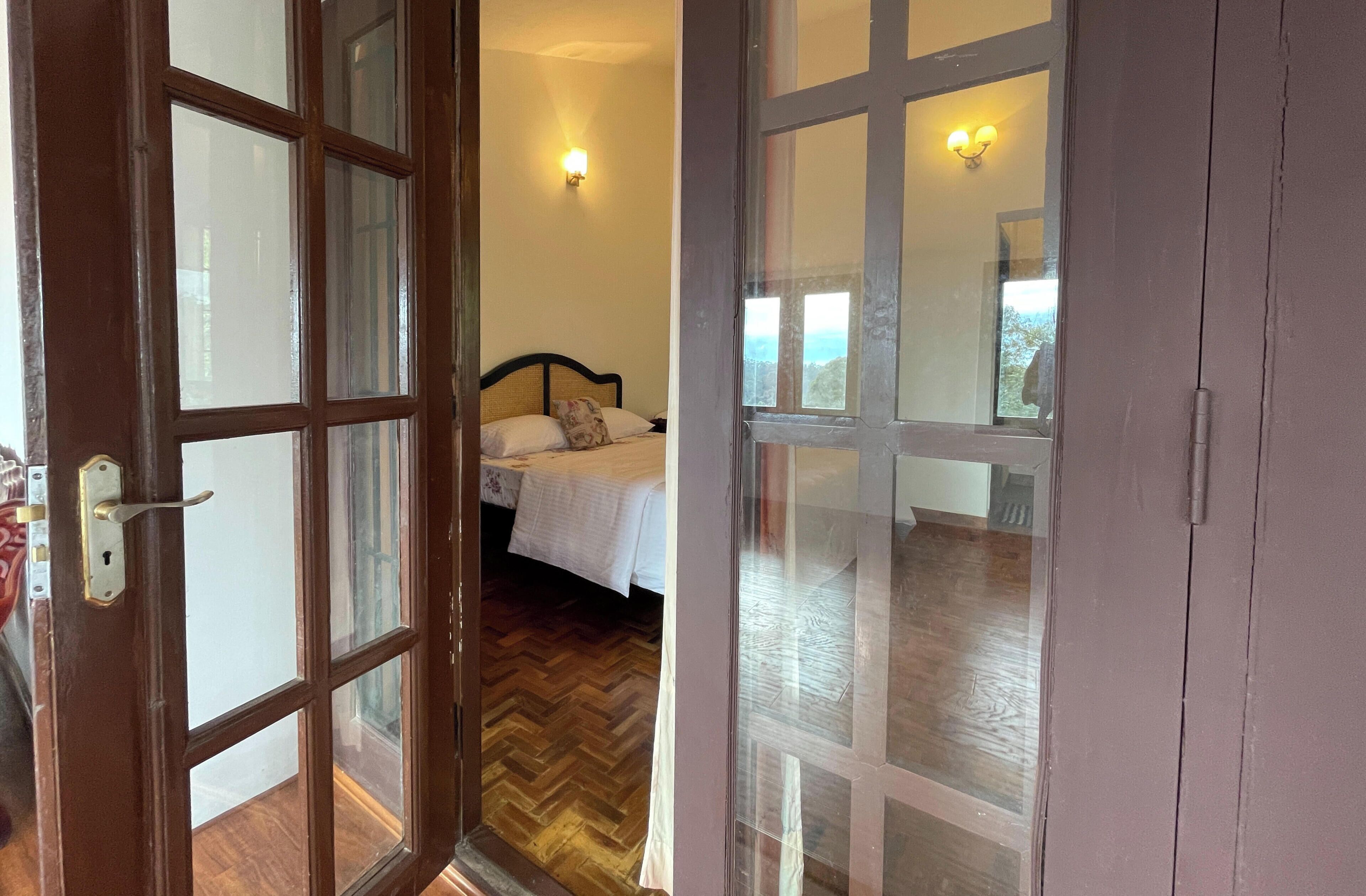 A room with a bed, a window, and a door with glass panels.