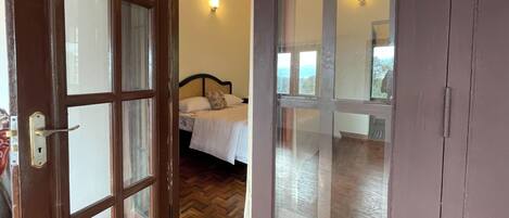 A room with a bed, a window, and a door with glass panels.