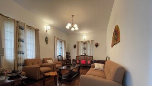Een woonkamer met een bank, fauteuils, een salontafel en een open haard.