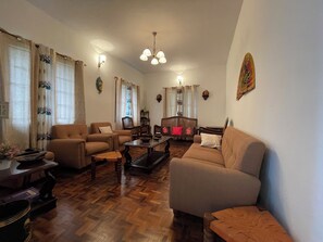 A living room with a sofa, armchairs, a coffee table, and a fireplace. - Nashika Villa by evaddo stays (Kodaikanal)