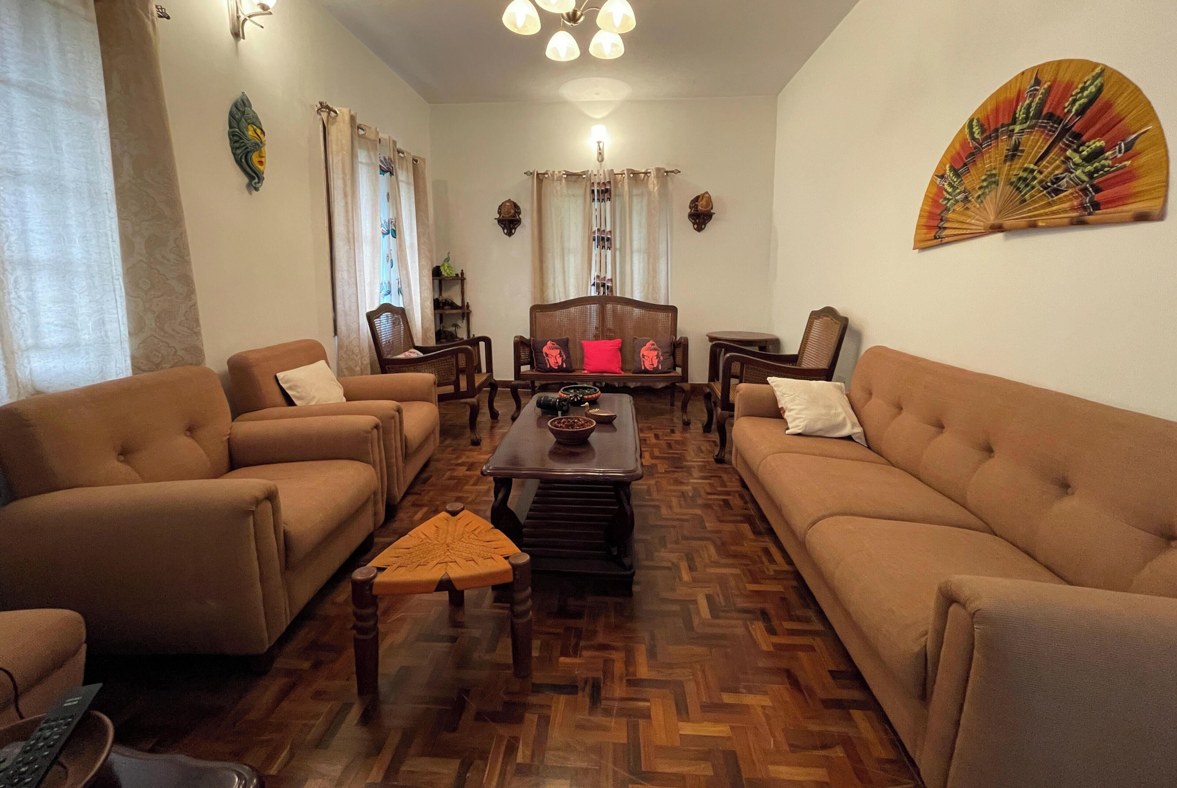 A living room with two sofas, a coffee table, and a decorative fan.