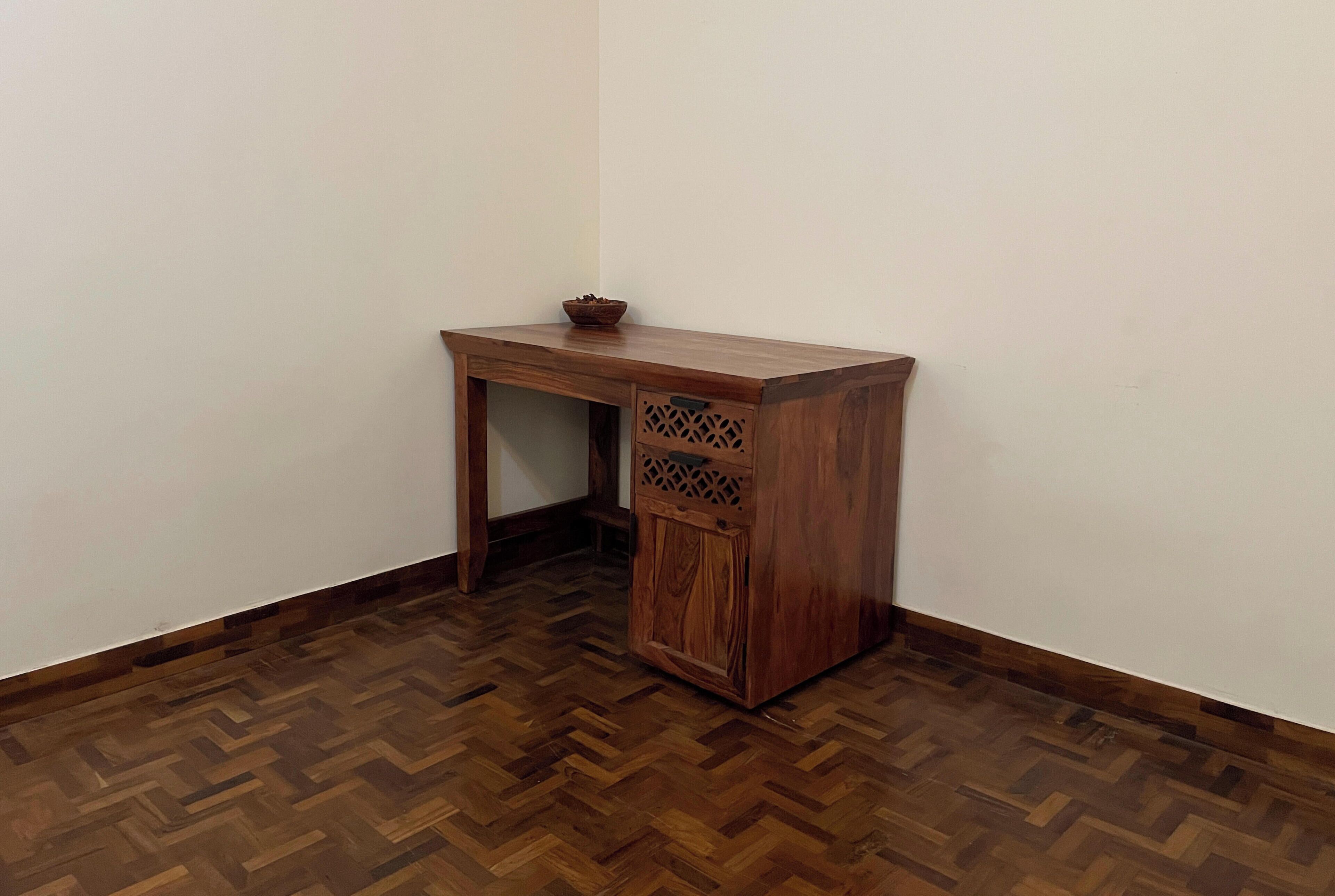 A corner room with a wooden desk and a herringbone-patterned floor.