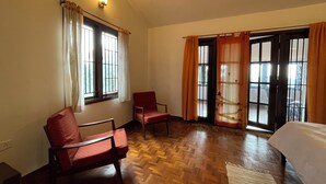 Een kamer met twee houten stoelen, een bed en een raam met gordijnen.