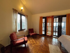 A room with two wooden chairs, a bed, and a window with curtains. - Nashika Villa by evaddo stays (Kodaikanal)