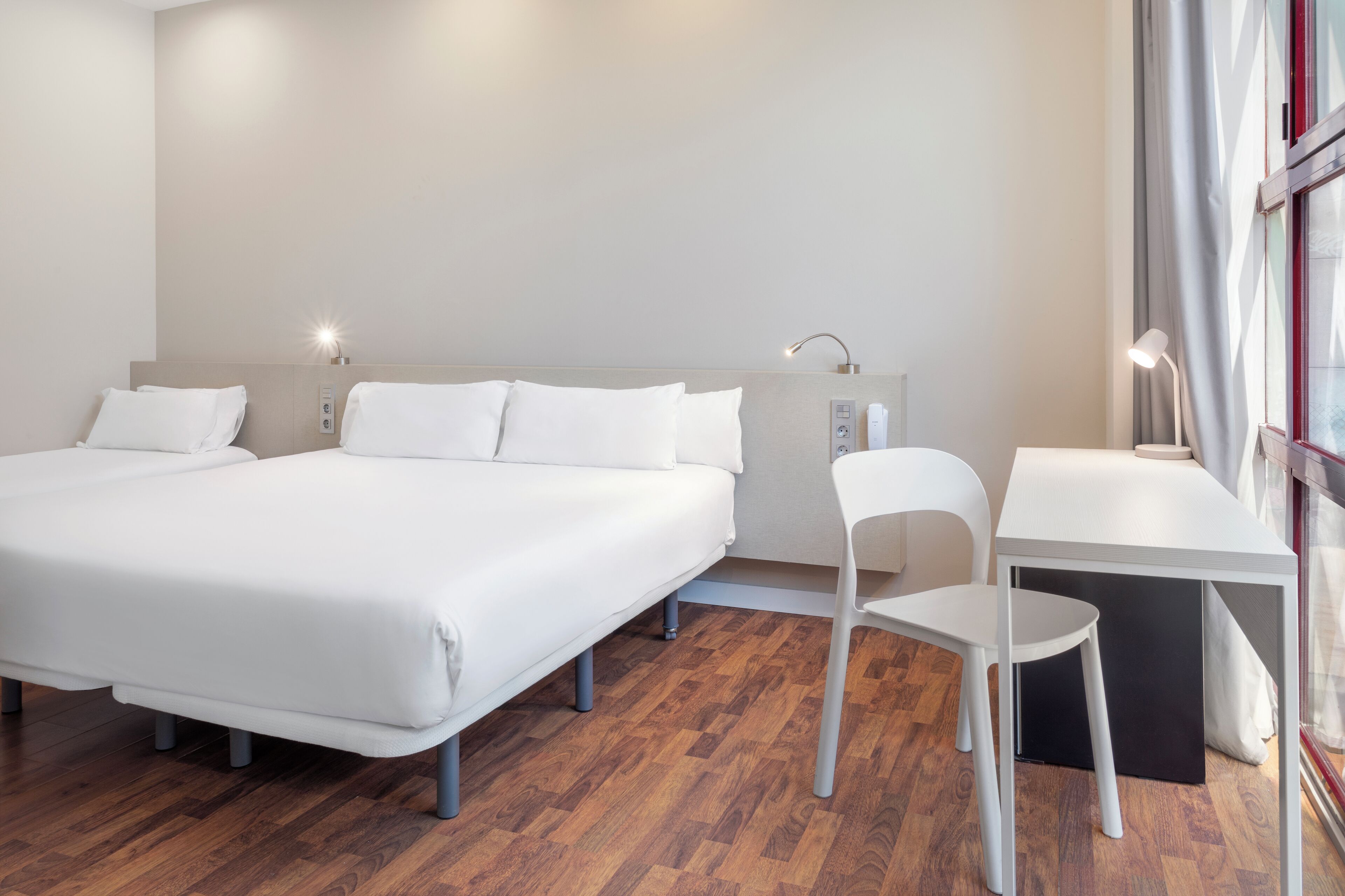 Una habitación de hotel moderna con una cama grande, un escritorio y una silla.
