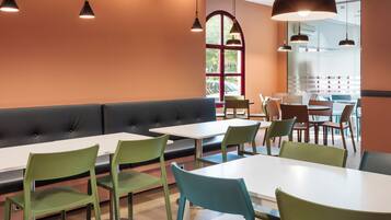 Interior de restaurant modern amb un taulell llarg, cadires verdes i una banca amb seients mullidors.