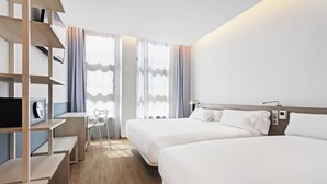 Une chambre d’hôtel avec deux lits, un bureau, une chaise et un téléviseur.
