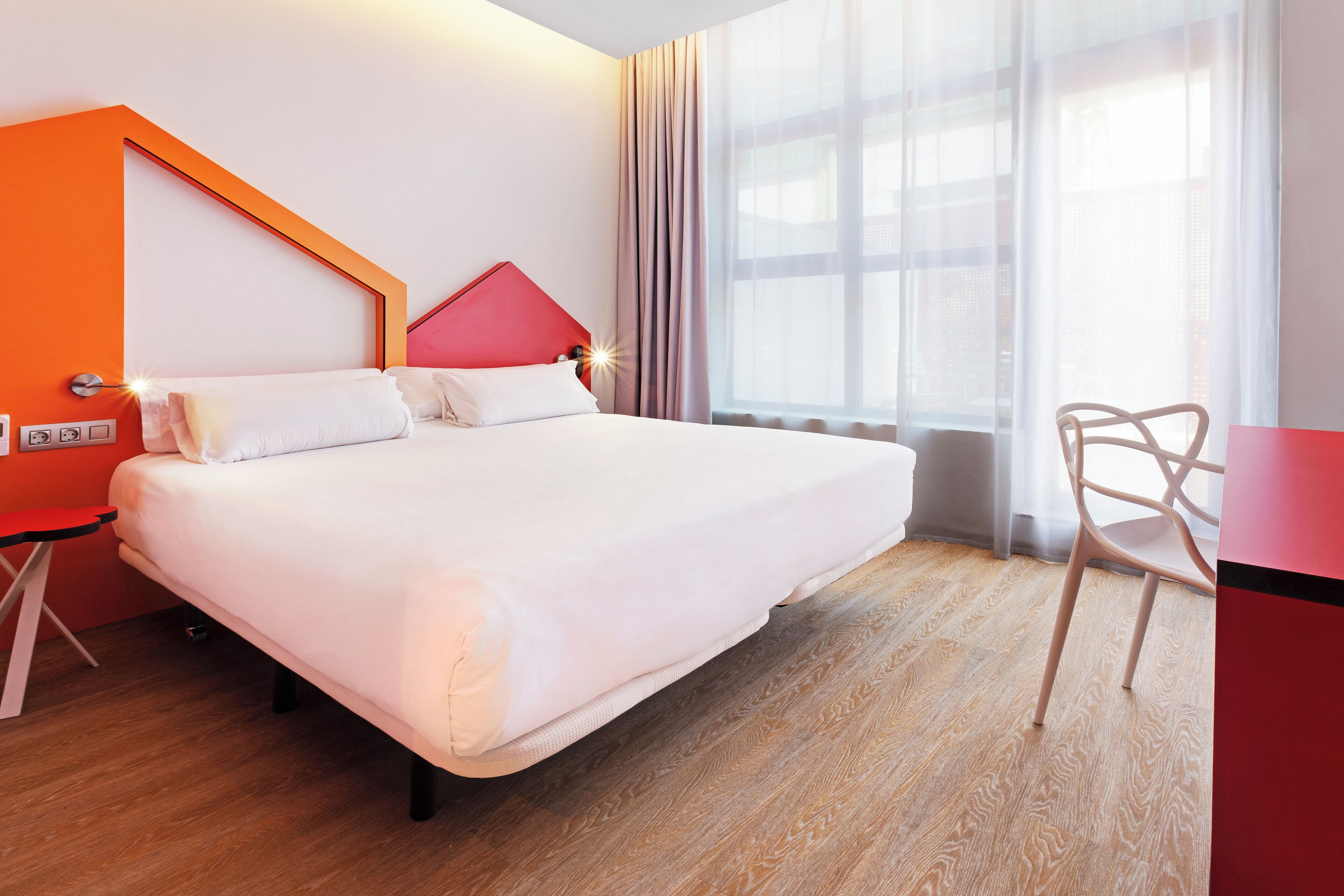 A hotel room with a large bed, a desk, and a chair.