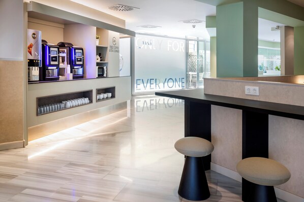 A modern bar area with self-service coffee machines, stools, and a glass partition with motivational text. - B&B Hotel Madrid Pinar de las Rozas (Las Rozas de Madrid)