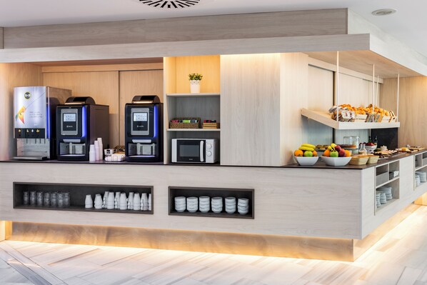 A modern kitchen area with built-in appliances, a coffee station, and a fruit bowl.
