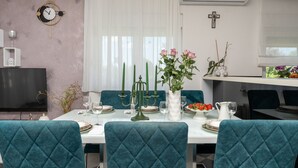 Ein Essbereich mit türkisfarbenen Sitzmöbeln, einem weißen Tisch gedeckt mit Tellern, Gläsern und einer Blumenvase.