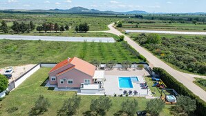 Ein Haus mit Swimmingpool, einem gepflasterten Einfahrt und Blick auf die umliegende Landschaft.
