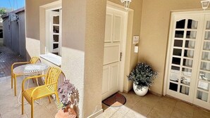 A covered patio with yellow chairs, a table, and a potted plant. - Unique accommodation in Parakladi (Αγιος Νικολαος)