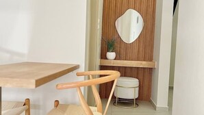 A modern dining area with a wooden table and chairs, a white bench, and a wall-mounted mirror. - Unique accommodation in Parakladi (Αγιος Νικολαος)