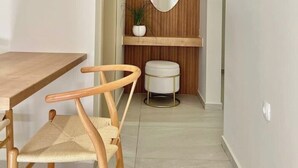 A narrow hallway with a wooden panel wall, a mirror, a small table, a chair, and a white bench. - Unique accommodation in Parakladi (Αγιος Νικολαος)