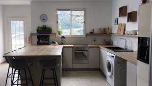 Une cuisine compacte dotée d’un îlot central, d’un four encastré et d’un lave-linge.