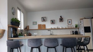 Une cuisine moderne avec un plan de travail en bois, des tabourets de bar et un sac suspendu.