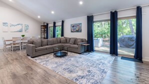 En moderne stue med en hjørnesofa, et sofabord og et spiseområde med bord og stole.