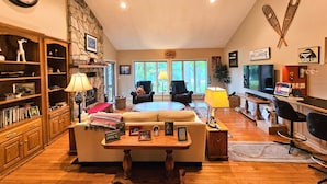 Una sala de estar acogedora con pared de piedra, muebles de madera, chimenea y televisor.