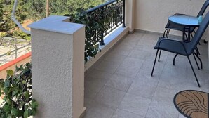 Ein Balkon mit Tisch und Stühlen, der einen schönen Blick auf das Meer und die grüne Landschaft bietet.