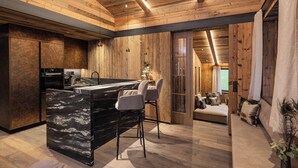 Eine moderne Küche mit einer Marmorinsel, Holzboden und einer gemütlichen Sitzecke inklusive Sofa und Kissen.