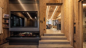 Ein modernes Interieur mit Kamin, Holzwänden und einer Treppe, die in einen Essbereich führt.