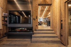 Un interior moderno con chimenea, paredes de madera y una escalera que lleva a un comedor.