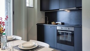 A modern kitchen with dark cabinetry, a stainless steel range hood, and a built-in oven. - Golden skyview from San Martino by Wonderful Italy (Genoa)