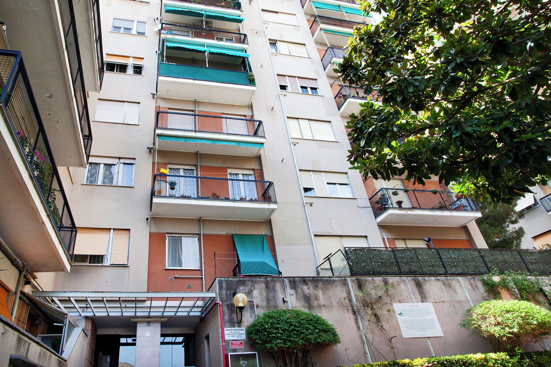 Un edificio residenziale a più piani con balconi, un ingresso ben visibile e un cartello che indica la presenza di una casella postale.
