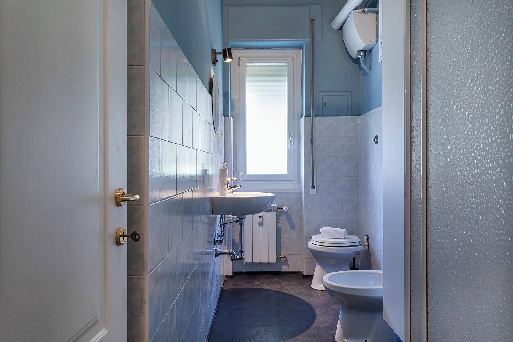 Une petite salle de bain avec un lavabo, des toilettes et une fenêtre.