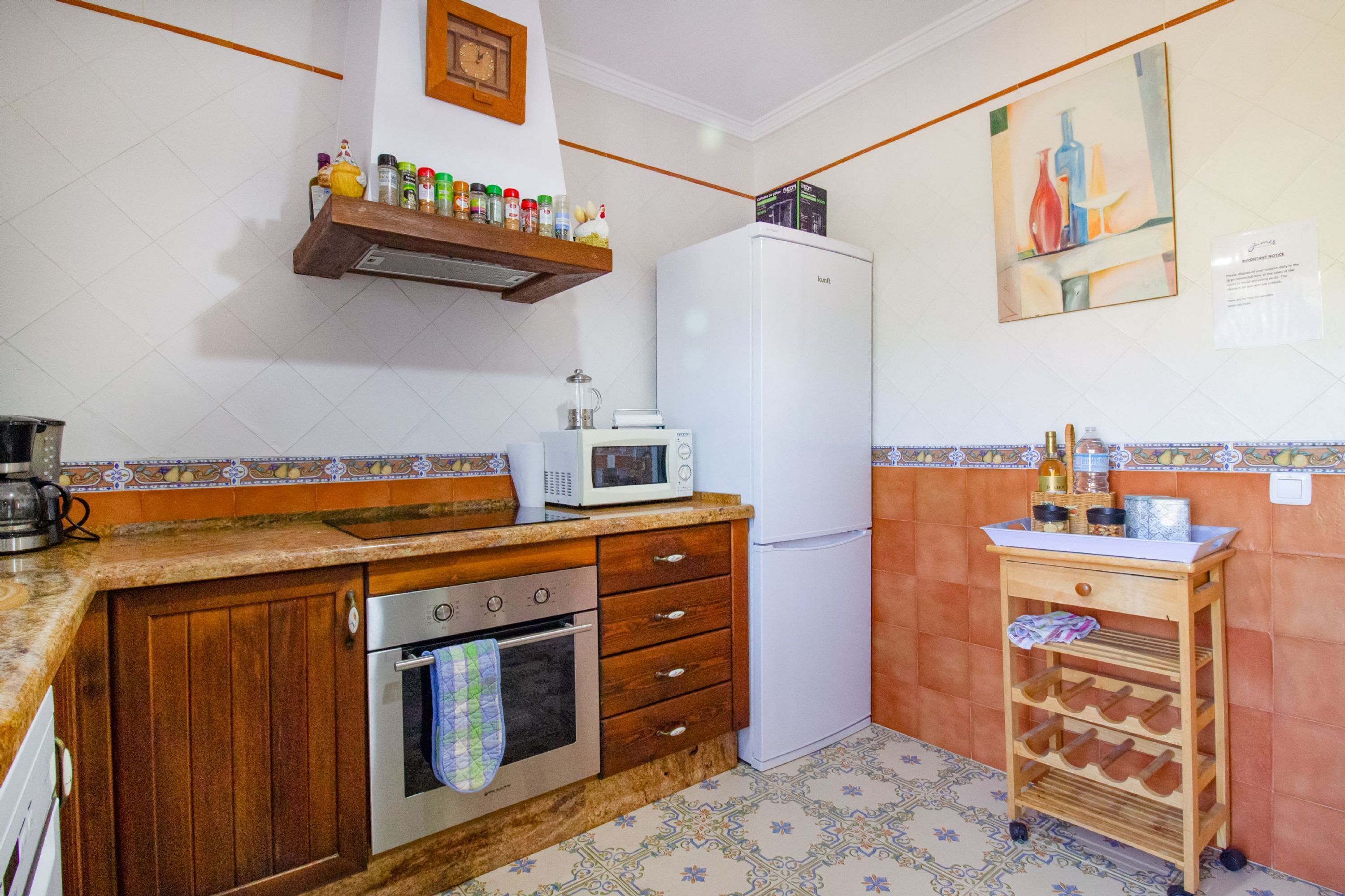 A kitchen with a wooden countertop, a white refrigerator, a microwave, and a wine rack.