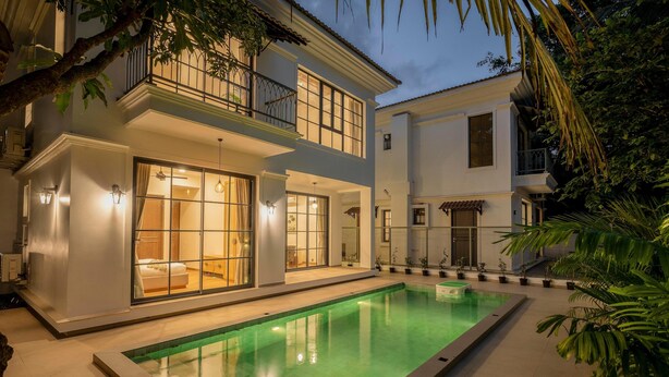 Una casa de dos pisos con piscina, ventanas amplias y un balcón.