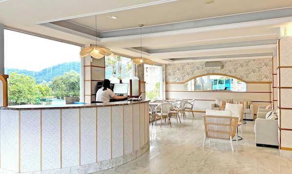 A reception area with a counter, seating, and a view of greenery.
