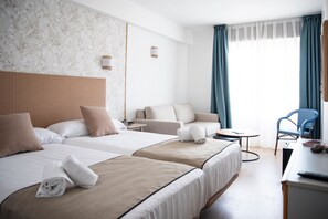Une chambre d’hôtel avec deux lits, un canapé, une petite table et une chaise.