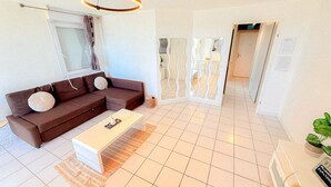 Un salon moderne avec un canapé marron, une table basse blanche et un luminaire suspendu.