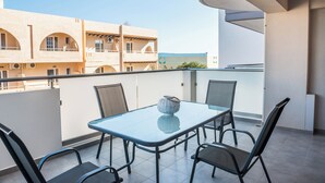 Un balcó amb una taula de vidre i quatre cadires, amb vista a un edifici amb finestres i balcons d'arc.