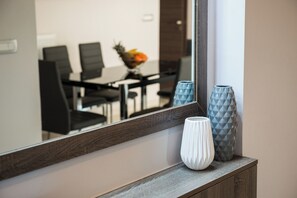 Een spiegel toont een eethoek met stoelen en een fruitschaal.