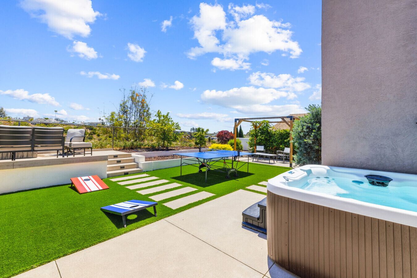 A backyard with a hot tub, a ping pong table, and a small pool.