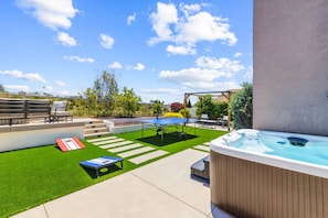 Un patio trasero con un jacuzzi, mesa de ping pong y una piscina pequeña.