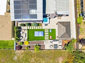 A rooftop with solar panels, a swimming pool, and a patio area with seating.