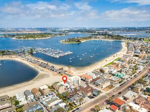 Luchtbeeld van een kustplaatsje met een jachthaven, zandstranden en woongebouwen.