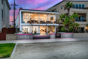 Een modern huis met twee verdiepingen, een balkon, grote ramen en een verzorgde tuin.